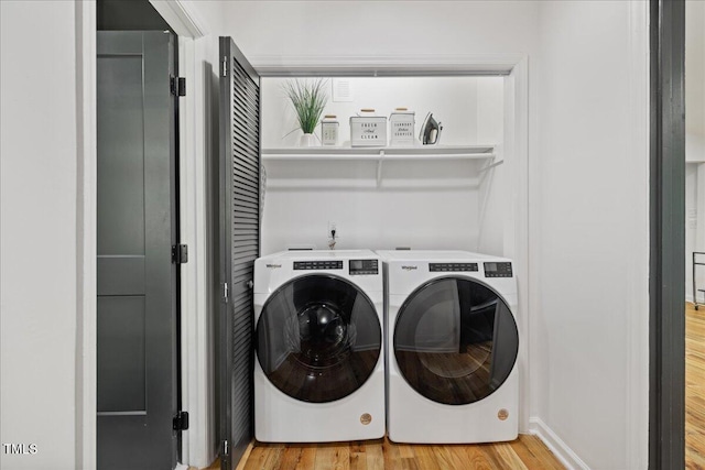 clothes washing area with laundry area, separate washer and dryer, and light wood finished floors