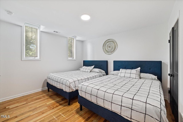 bedroom with visible vents, baseboards, and wood finished floors