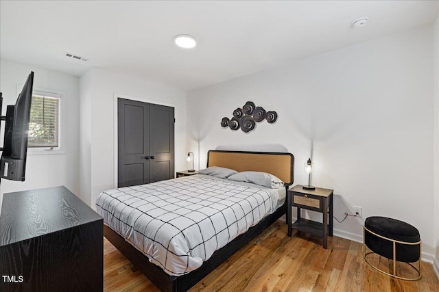 bedroom featuring visible vents, baseboards, and wood finished floors