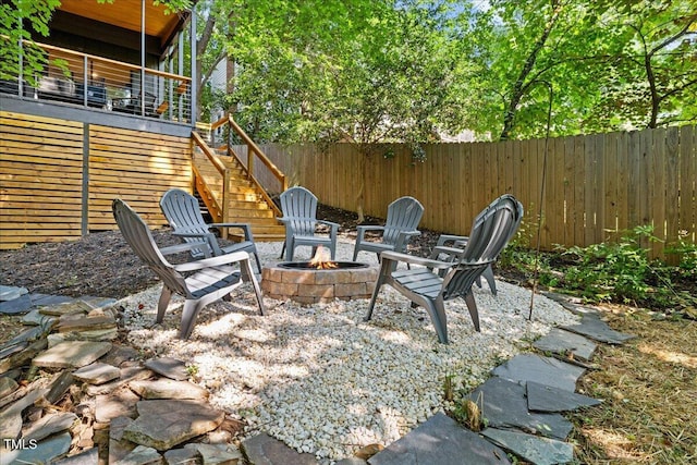 view of patio / terrace featuring an outdoor fire pit, fence, and stairway