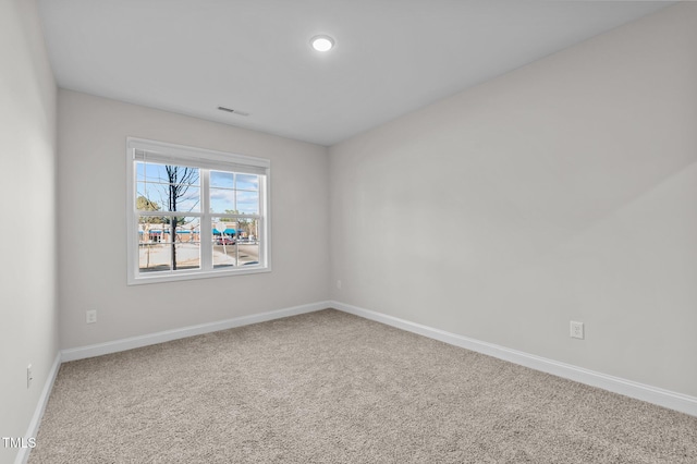 spare room with carpet flooring, visible vents, and baseboards