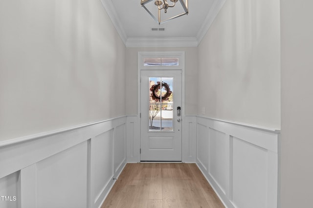 entryway with a wainscoted wall, crown molding, visible vents, a decorative wall, and light wood-style floors