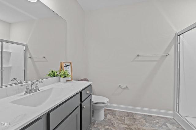 full bath featuring stone finish floor, a shower stall, baseboards, and vanity