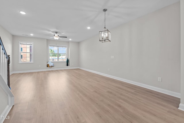 unfurnished living room with recessed lighting, baseboards, stairway, light wood-type flooring, and ceiling fan with notable chandelier