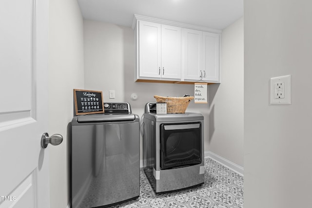 washroom with light tile patterned floors, separate washer and dryer, cabinet space, and baseboards