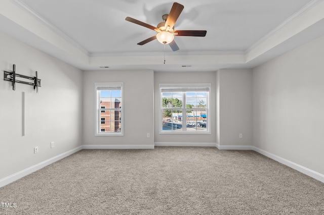 empty room featuring baseboards, a raised ceiling, and crown molding