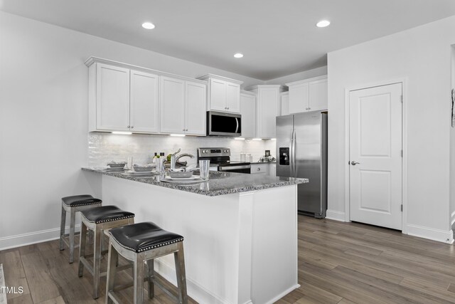 332 Church St Unit 45, Wendell, NC 27591 - kitchen featuring stainless steel appliances, white cabinetry, a peninsula, dark wood finished floors, and tasteful backsplash