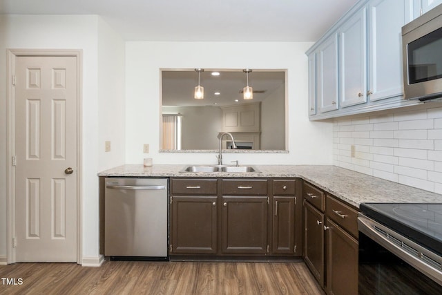 kitchen with wood finished floors, appliances with stainless steel finishes, a sink, and dark brown cabinetry