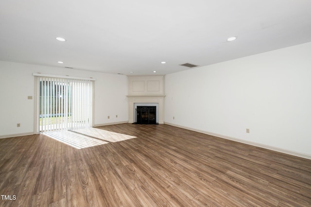 unfurnished living room with a fireplace, baseboards, wood finished floors, and recessed lighting