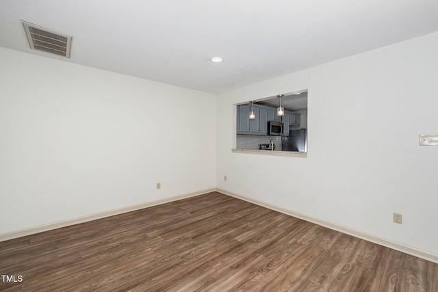 unfurnished room featuring dark wood-style floors, baseboards, and visible vents