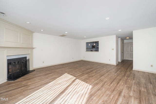 unfurnished living room featuring light wood finished floors, a fireplace, baseboards, and recessed lighting