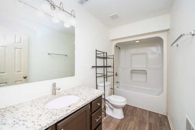 bathroom with toilet, vanity, wood finished floors, and visible vents