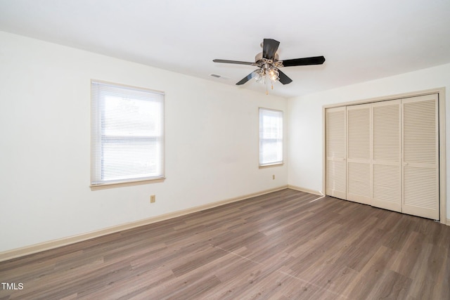 unfurnished bedroom featuring wood finished floors, a ceiling fan, visible vents, baseboards, and a closet