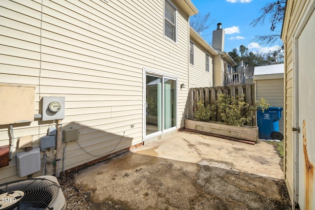 view of side of property with central AC, a patio, a chimney, and fence