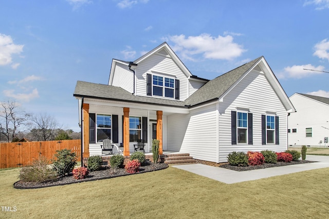 view of front of house featuring a shingled roof, a front yard, covered porch, and fence