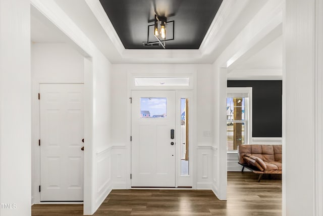 foyer entrance featuring a tray ceiling, dark wood-type flooring, wainscoting, and crown molding