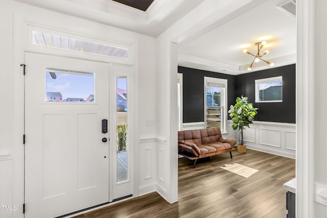 entrance foyer featuring ornamental molding, a wainscoted wall, and wood finished floors