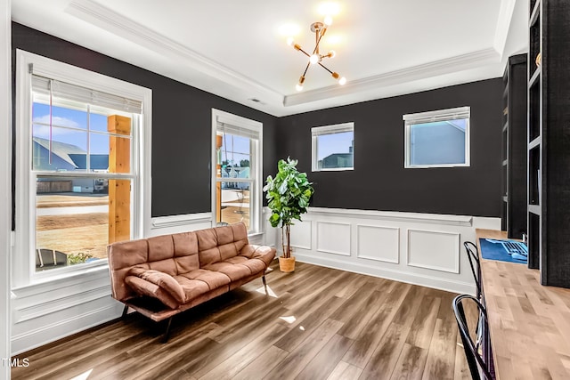 sitting room featuring a tray ceiling, a wealth of natural light, ornamental molding, wood finished floors, and a chandelier