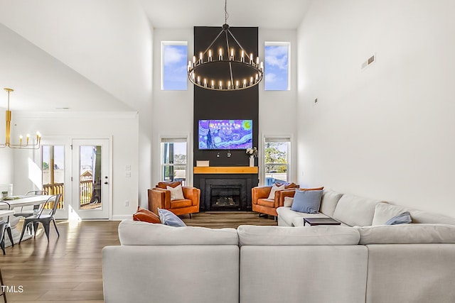 living room featuring a fireplace, visible vents, wood finished floors, a chandelier, and baseboards