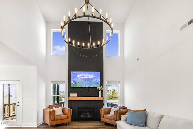 living area featuring an inviting chandelier, a fireplace, visible vents, and wood finished floors