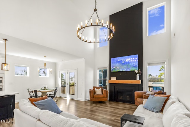 living room featuring a large fireplace, baseboards, a towering ceiling, wood finished floors, and crown molding