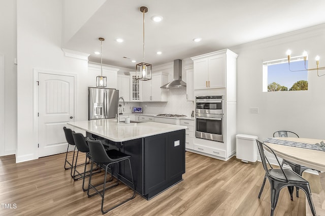 kitchen featuring stainless steel appliances, a sink, light countertops, backsplash, and wall chimney exhaust hood