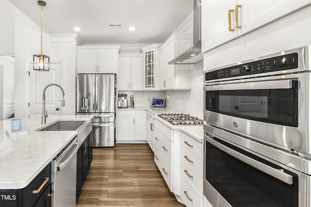 kitchen with stainless steel appliances, white cabinetry, wall chimney exhaust hood, and tasteful backsplash