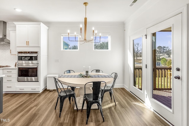 dining room featuring baseboards, a chandelier, wood finished floors, and crown molding