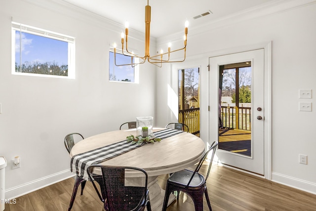 dining space featuring baseboards, dark wood finished floors, visible vents, and crown molding