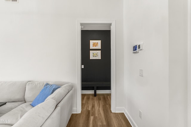 hall featuring dark wood-style floors, visible vents, and baseboards