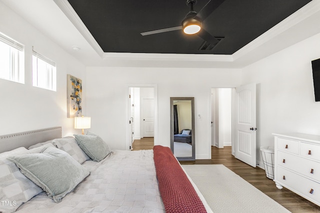 bedroom with a raised ceiling, visible vents, ceiling fan, and wood finished floors