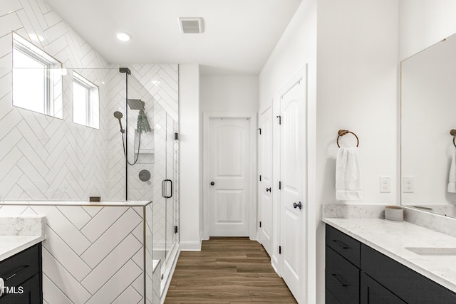 full bathroom with recessed lighting, visible vents, a shower stall, vanity, and wood finished floors