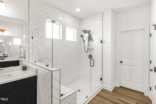 full bath featuring baseboards, a shower stall, vanity, and wood finished floors