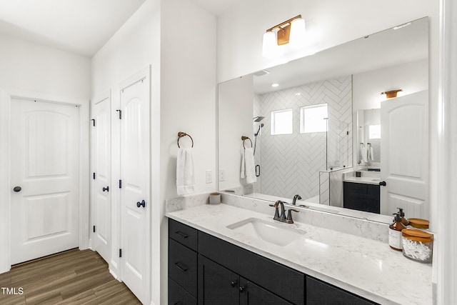 bathroom featuring wood finished floors, a shower stall, and vanity