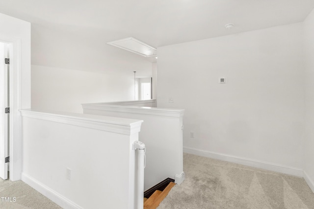 hall featuring carpet floors, attic access, baseboards, and an upstairs landing