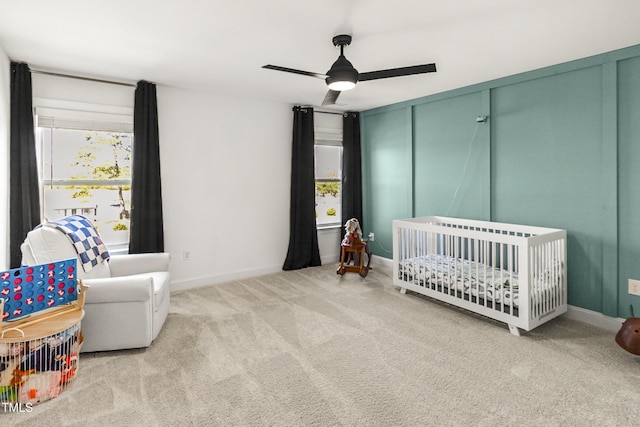 bedroom featuring a crib, carpet, a ceiling fan, and baseboards