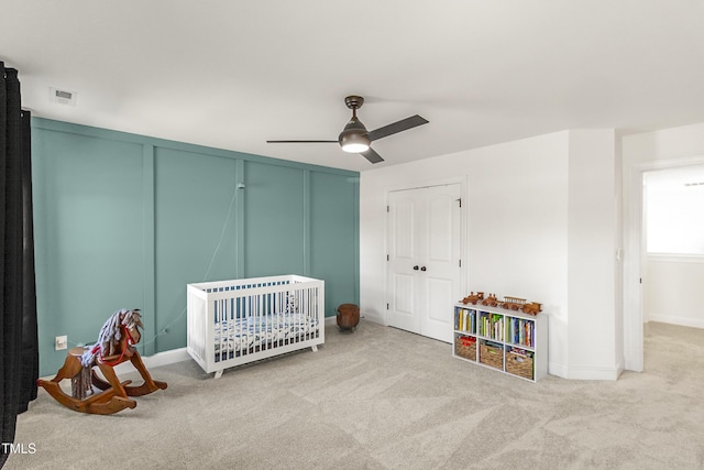 bedroom featuring carpet floors, ceiling fan, visible vents, and a decorative wall