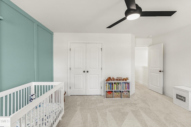 bedroom featuring a ceiling fan, a nursery area, a closet, and carpet flooring