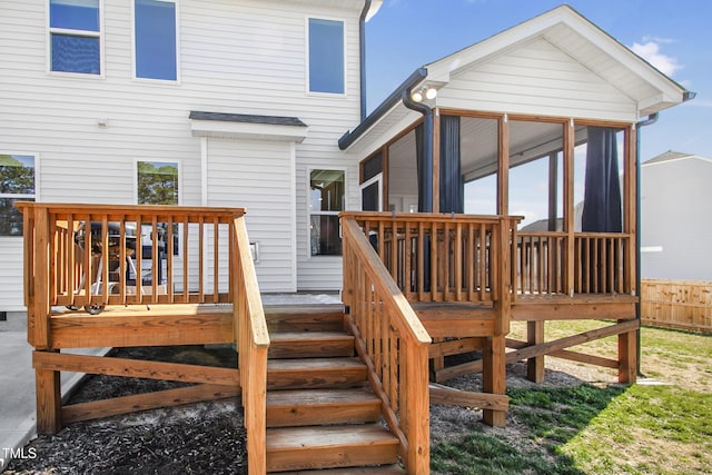 wooden deck featuring a sunroom, fence, and stairs