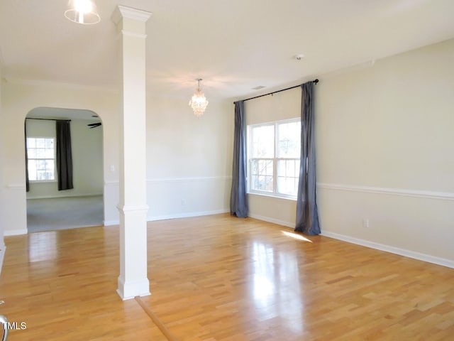 unfurnished room featuring plenty of natural light, decorative columns, and arched walkways