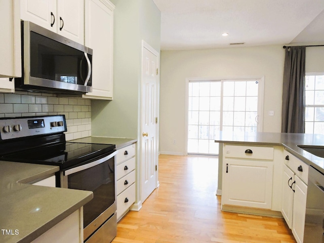 kitchen with white cabinets, decorative backsplash, stainless steel appliances, light wood-type flooring, and recessed lighting