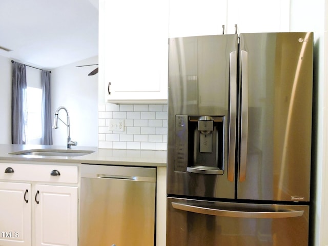 kitchen featuring tasteful backsplash, appliances with stainless steel finishes, white cabinets, a sink, and ceiling fan