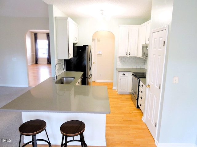 kitchen featuring a peninsula, appliances with stainless steel finishes, arched walkways, and a sink