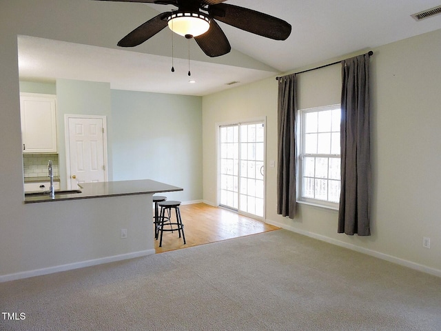 unfurnished room with baseboards, a sink, visible vents, and light colored carpet