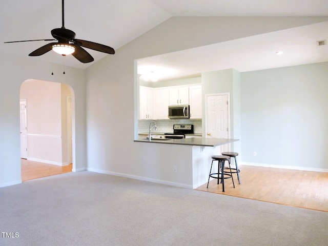 kitchen with arched walkways, decorative backsplash, appliances with stainless steel finishes, white cabinetry, and a sink