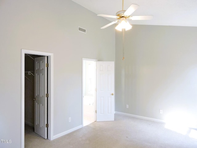 unfurnished bedroom with high vaulted ceiling, light colored carpet, visible vents, a closet, and a walk in closet