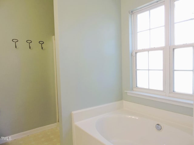 bathroom featuring walk in shower, a garden tub, and baseboards