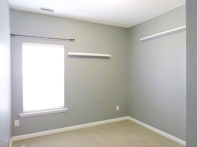 carpeted spare room with visible vents and baseboards