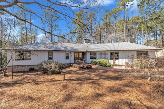 view of front of home featuring metal roof, crawl space, and a chimney