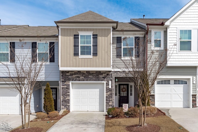 multi unit property with a garage, stone siding, board and batten siding, and concrete driveway